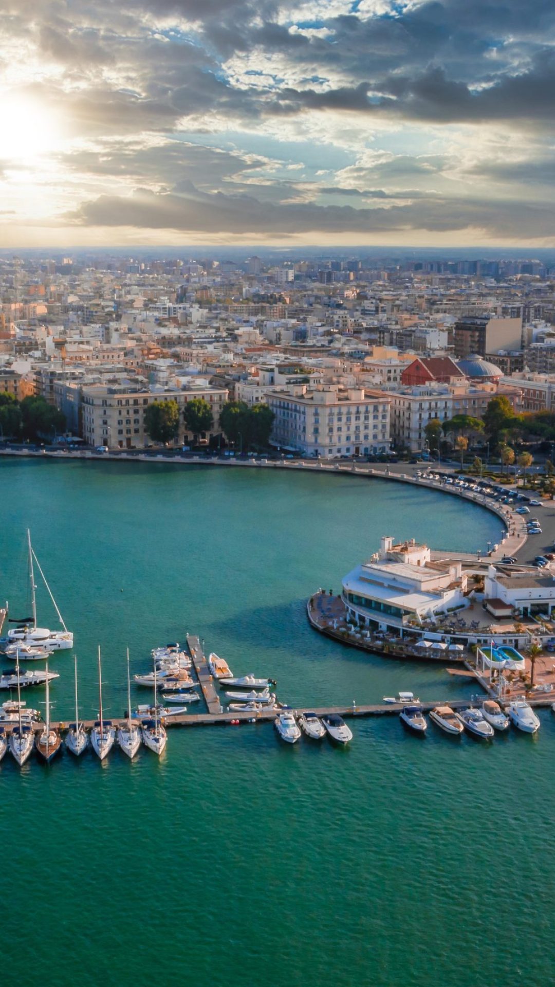 Beautiful panoramic aerial view photo from flying drone at sunset to Bari Apulia City port boats and yachts Sea Coastline, Teatro Margherita, and Bari city skyline.